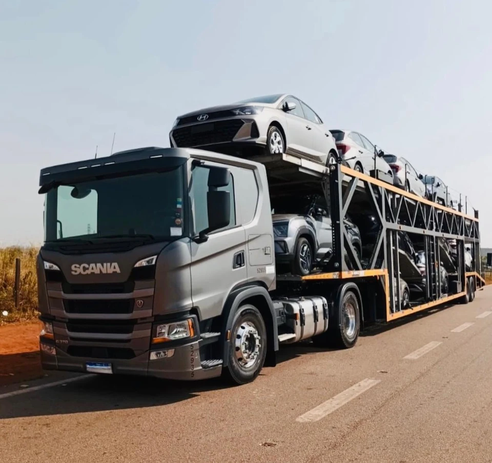 Caminhão-cegonha Scania transportando veículos de passeio na rodovia.